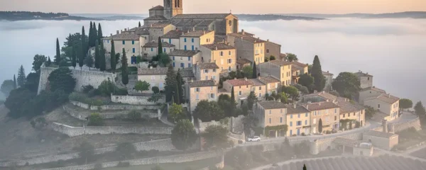 Village perché de Gordes émergeant de la brume matinale avec ses pierres dorées typiques du Luberon